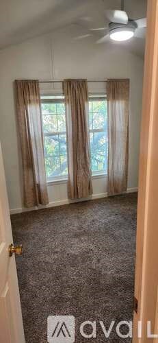 A room with a carpeted floor and a window with curtains.
