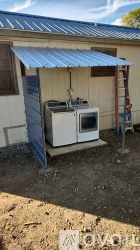 A small outdoor kitchen with a stove and oven under a metal roof.