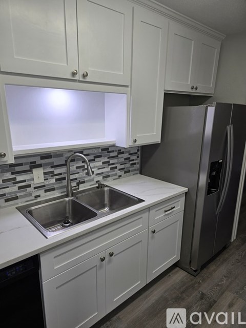 A kitchen with white cabinets and a stainless steel refrigerator.