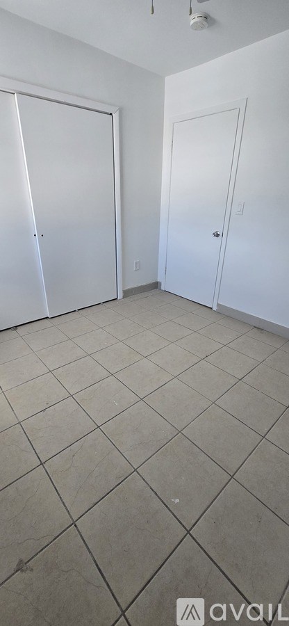 A room with two white doors and a tiled floor.