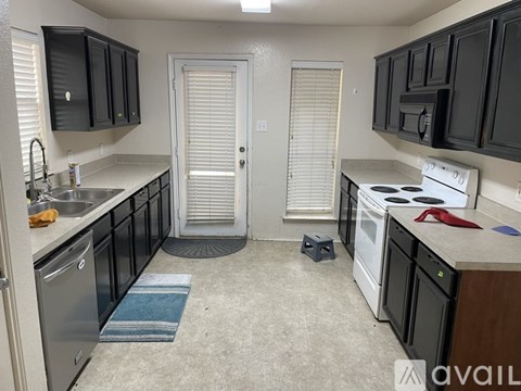 A kitchen with black cabinets and a white stove top oven.