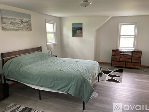 A bedroom with a bed, dresser, and window.