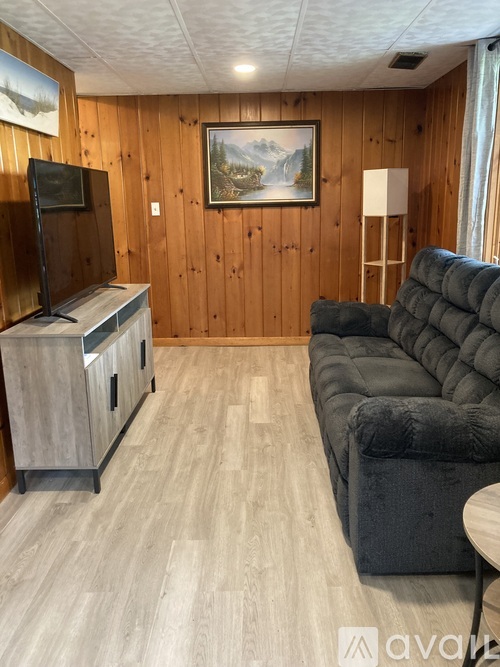 A living room with a grey couch, wooden cabinets, and a painting on the wall.