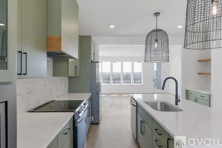 A modern kitchen with green cabinets and a marble countertop.