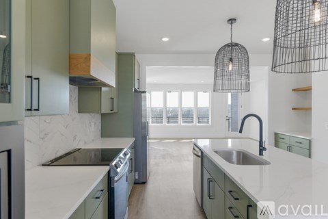 A modern kitchen with green cabinets and a marble countertop.