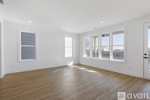 A spacious room with wooden flooring and large windows.