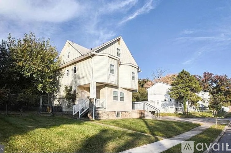 A two-story house with a front porch and a tree in front.