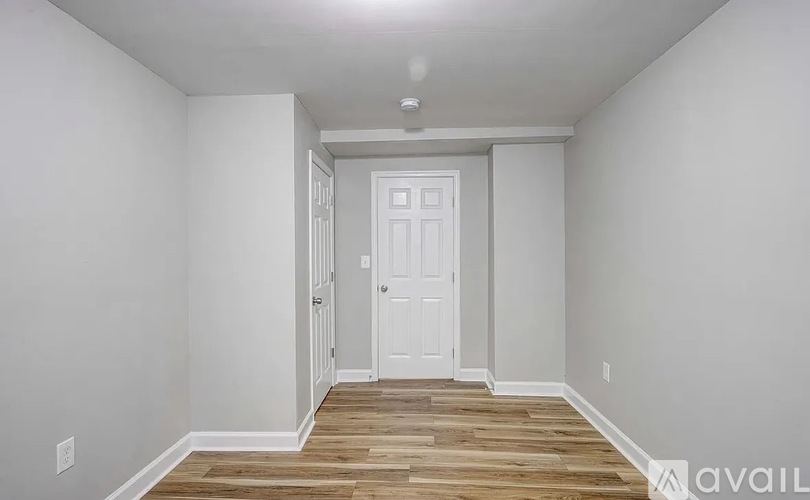 A room with a white door and wooden flooring.