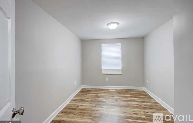A room with wooden flooring and a window with blinds.