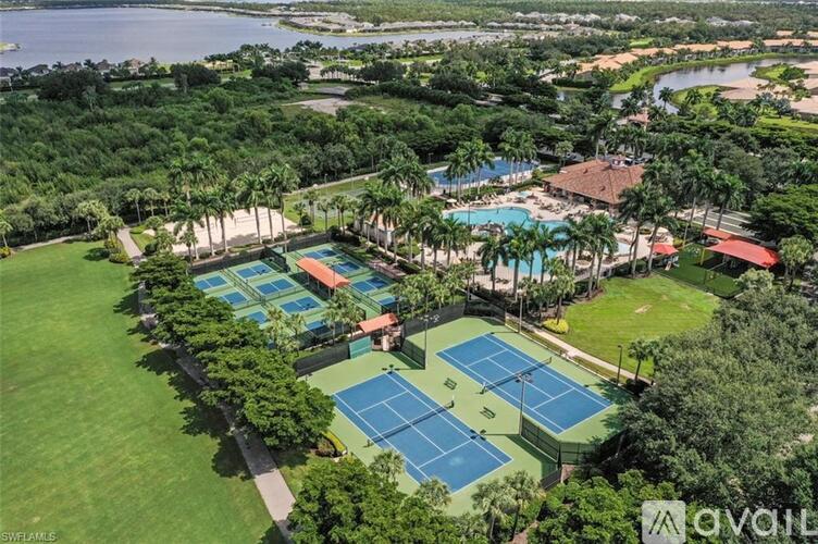 An aerial view of a tennis court surrounded by trees and a pool.