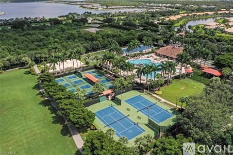 An aerial view of a tennis court surrounded by trees and a pool.