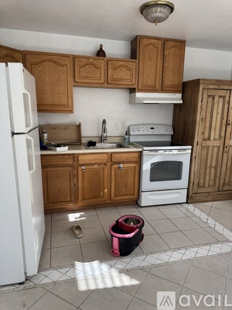 A kitchen with wooden cabinets and a white fridge.