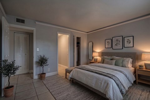 A bedroom with a large bed and a potted plant.