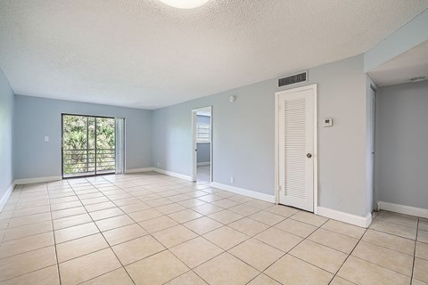 A spacious room with a sliding glass door leading to a balcony.