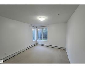 A large empty room with a window and a sliding door.