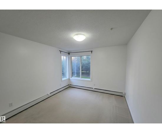 A large empty room with a window and a sliding door.