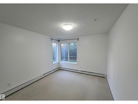 A large empty room with a window and a sliding door.