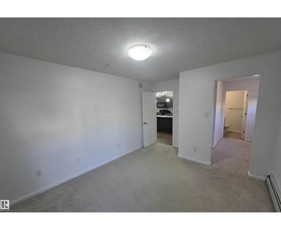 A spacious room with a doorway leading to another room.