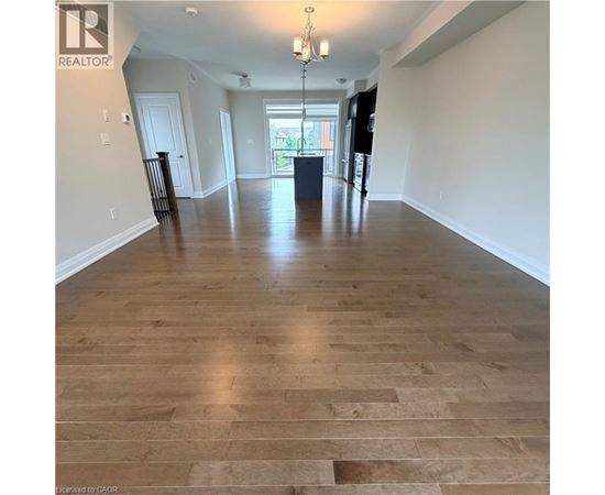 A spacious room with wooden flooring and a chandelier.