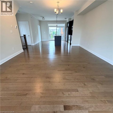 A spacious room with wooden flooring and a chandelier.