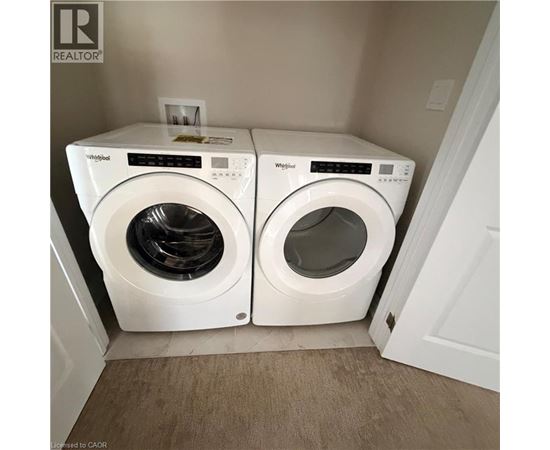 Two white Whirlpool washing machines in a small laundry room.