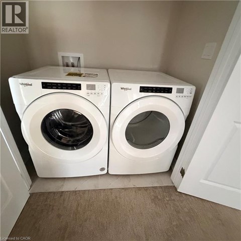 Two white Whirlpool washing machines in a small laundry room.