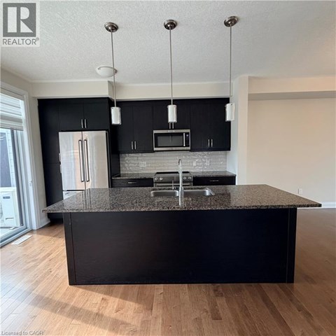 A modern kitchen with black cabinets and a granite countertop.