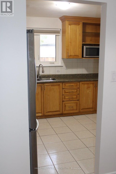 A kitchen with wooden cabinets and a refrigerator.