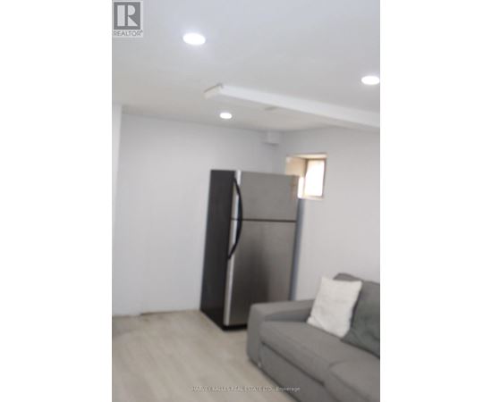 A modern living room with a grey couch and a black refrigerator.