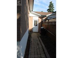A white door is on the left side of a brick building.