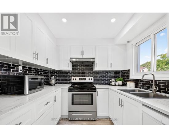 A modern kitchen with white cabinets and black backsplash.