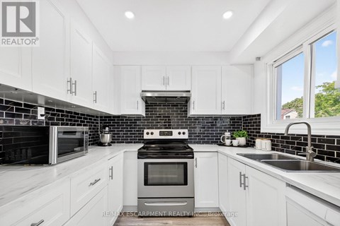 A modern kitchen with white cabinets and black backsplash.