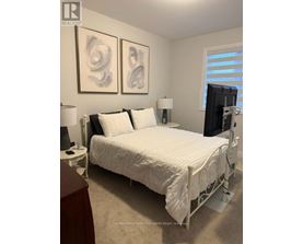 A bedroom with a white bed and two abstract paintings on the wall.