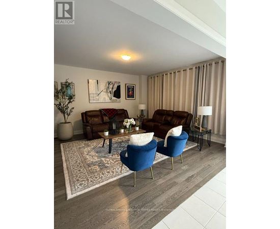 A living room with a brown couch, blue armchair, and a coffee table with a vase of flowers on it.