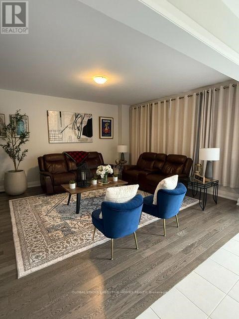 A living room with a brown couch, blue armchair, and a coffee table with a vase of flowers on it.