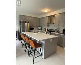 A kitchen with a long island and brown chairs.