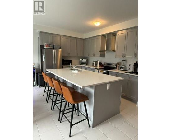 A kitchen with a long island and brown chairs.