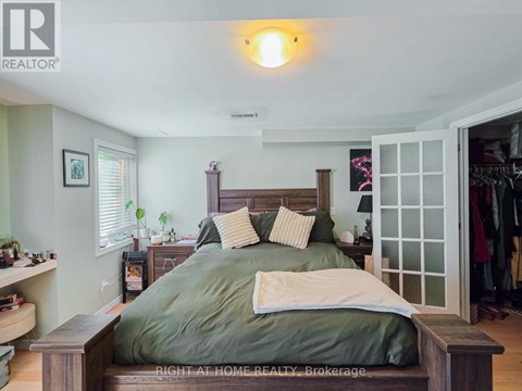 A bedroom with a bed in the center and a wooden headboard.
