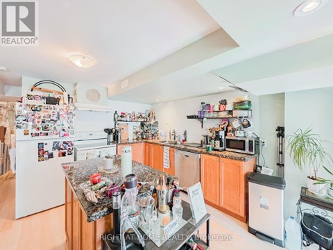 A kitchen with a refrigerator covered in magnets and a counter with a blender on it.