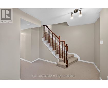 A staircase with a wooden handrail and beige carpeted steps.