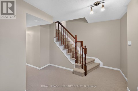 A staircase with a wooden handrail and beige carpeted steps.