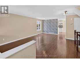 A spacious room with wooden flooring and a stone wall.