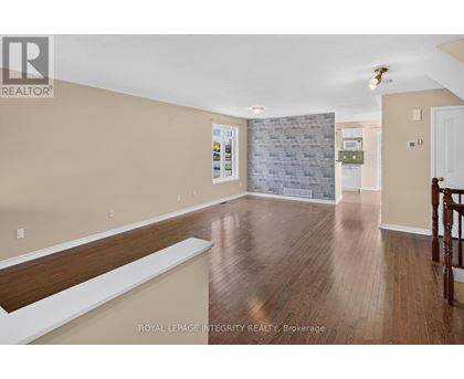 A spacious room with wooden flooring and a stone wall.