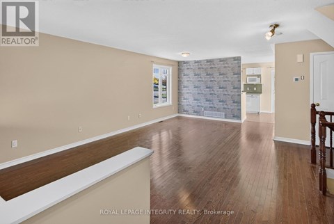 A spacious room with wooden flooring and a stone wall.
