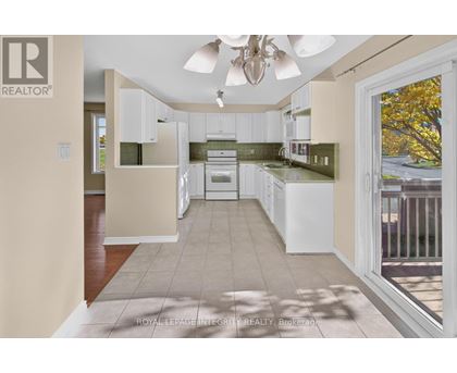 A well-lit kitchen with white cabinets and a ceiling fan.