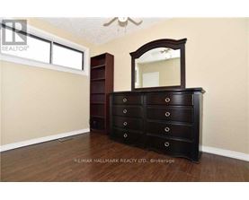 A bedroom with a large wooden dresser and a mirror.