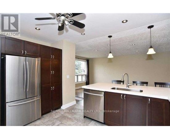 A kitchen with a stainless steel refrigerator and brown cabinets.