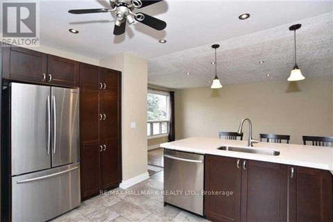 A kitchen with a stainless steel refrigerator and brown cabinets.