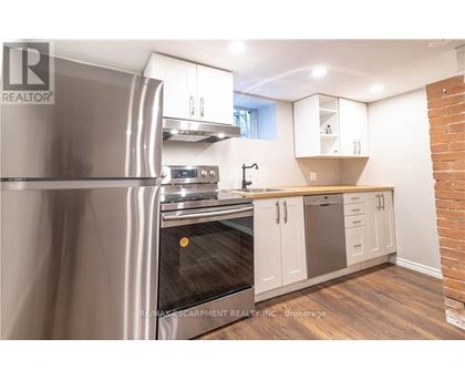 A modern kitchen with a stainless steel refrigerator and wooden flooring.