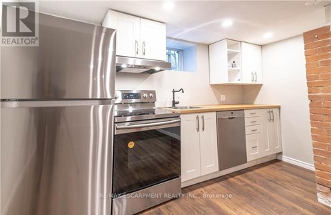 A modern kitchen with a stainless steel refrigerator and wooden flooring.